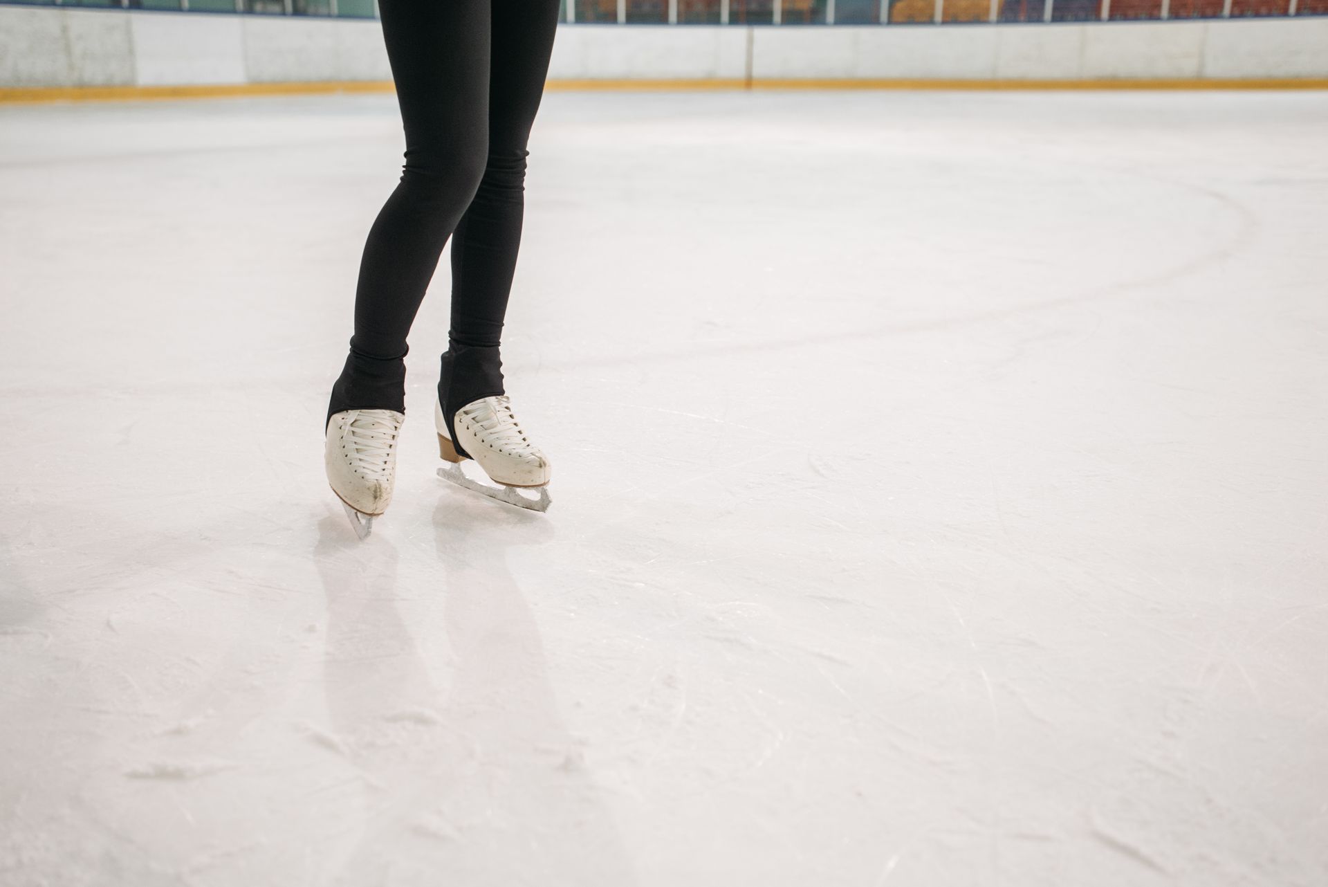 Figure skater's legs and white skates on ice rink