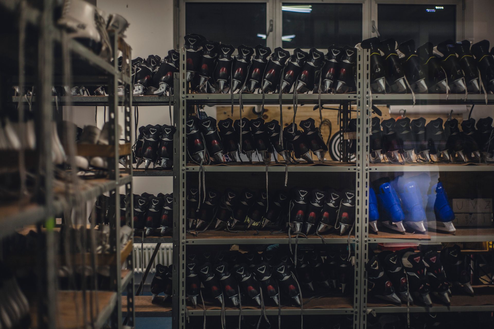 Black and red hockey skates organized on industrial metal shelving