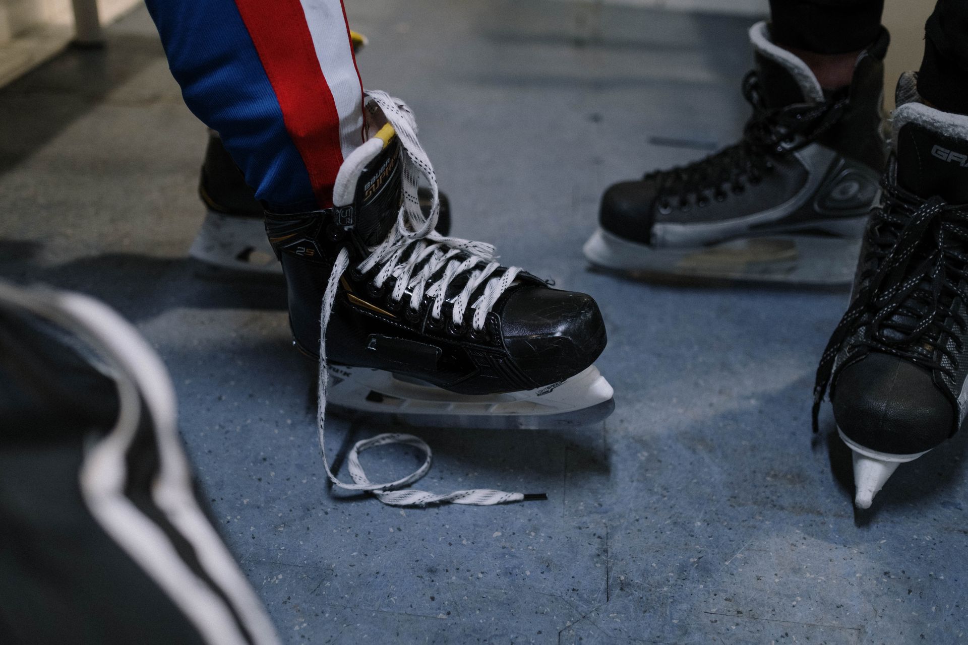 Hockey skates with blue-red-white socks on ice rink surface