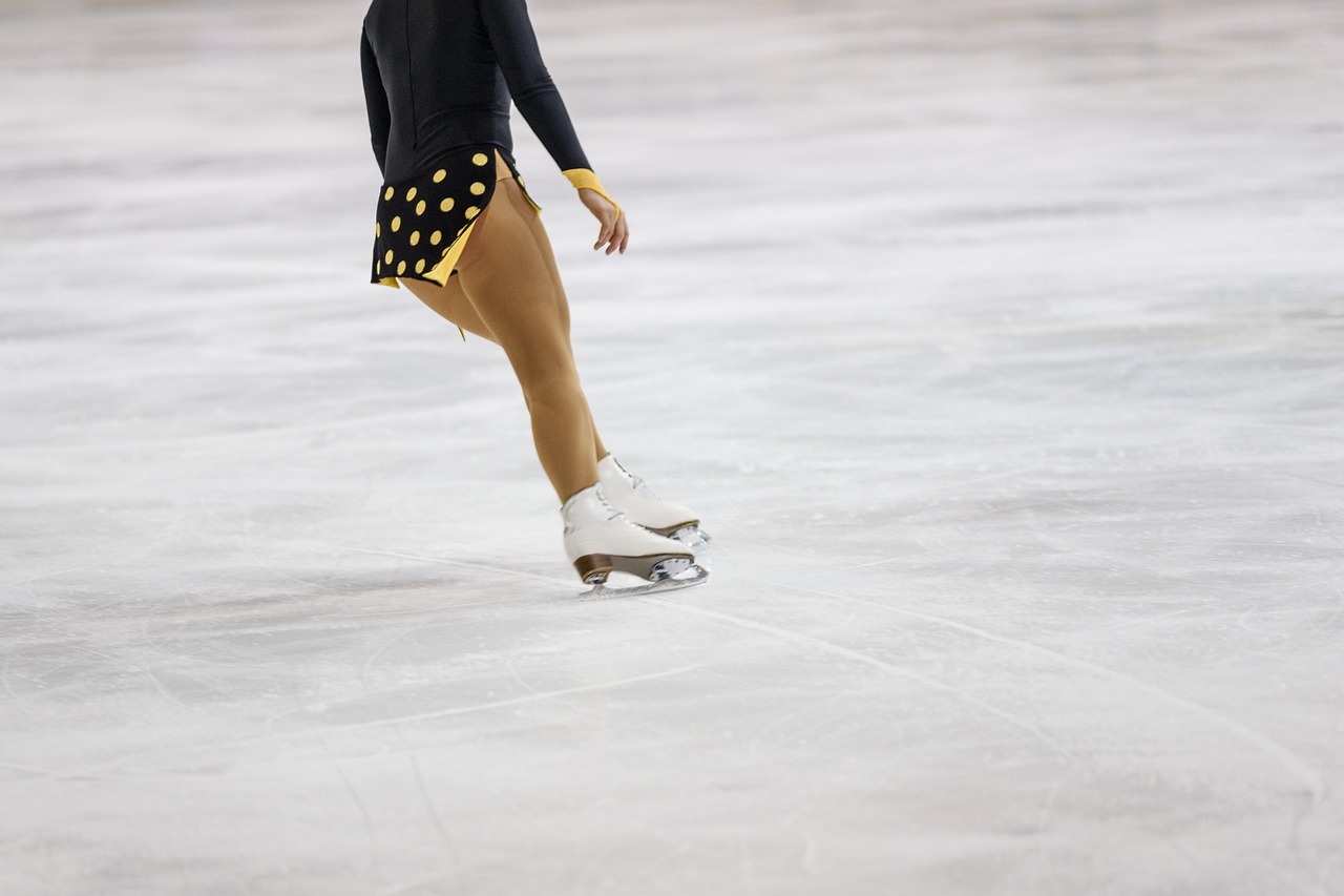 Figure skater's lower body performing on ice with decorative skirt