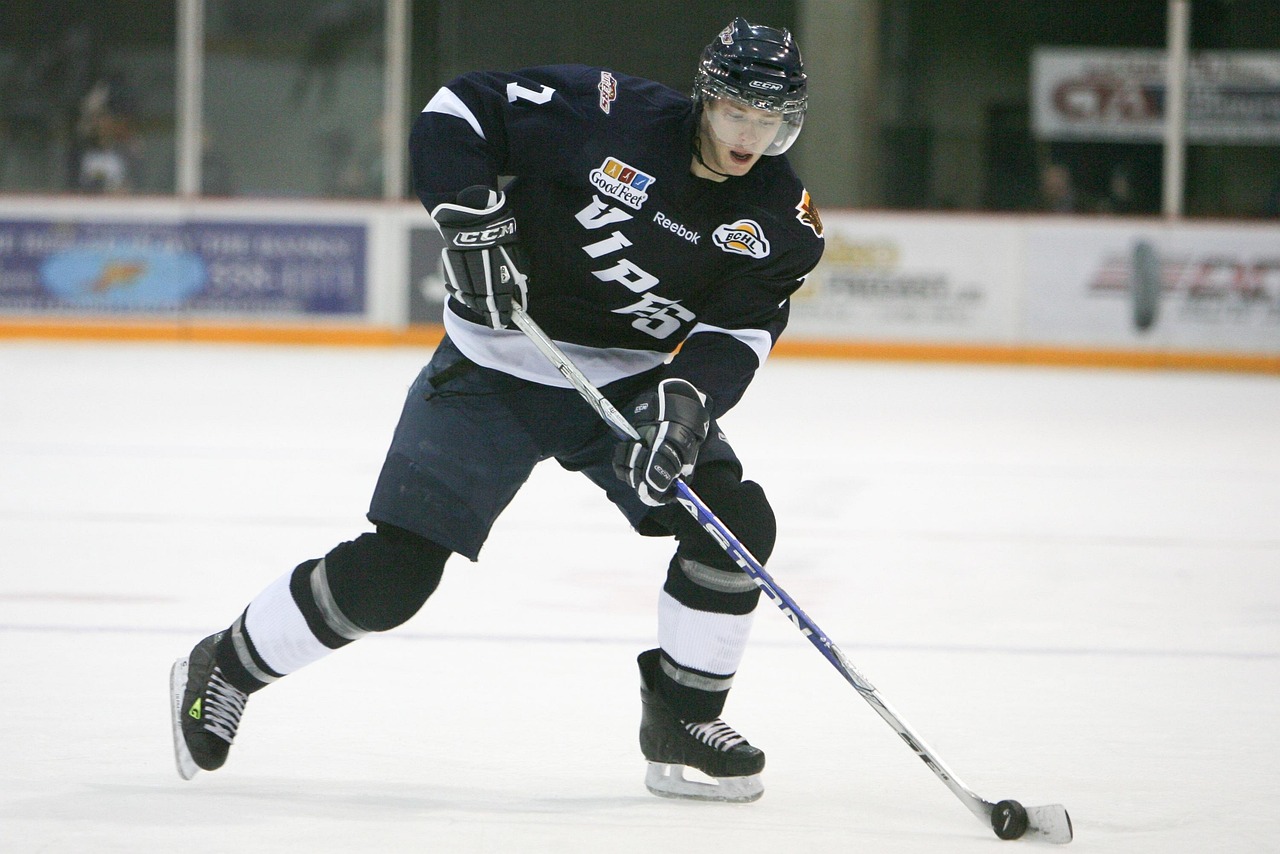 Hockey player in action with stick and puck on ice rink during game