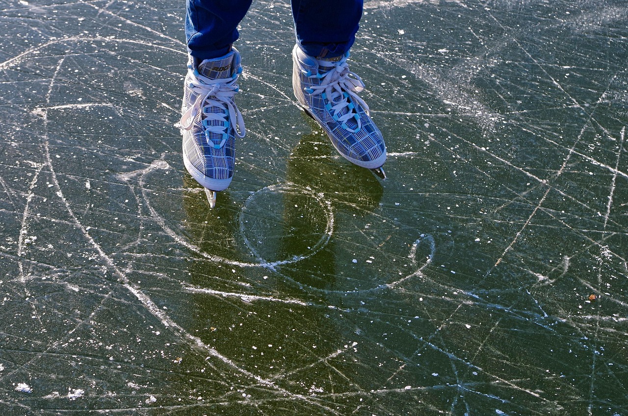 Person ice skating on frozen lake with visible cracks and algae